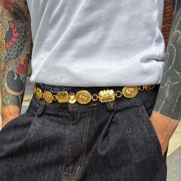 Person wearing a gold belt with decorative elements, white shirt, and dark jeans. Gold Chain Belt for Men
